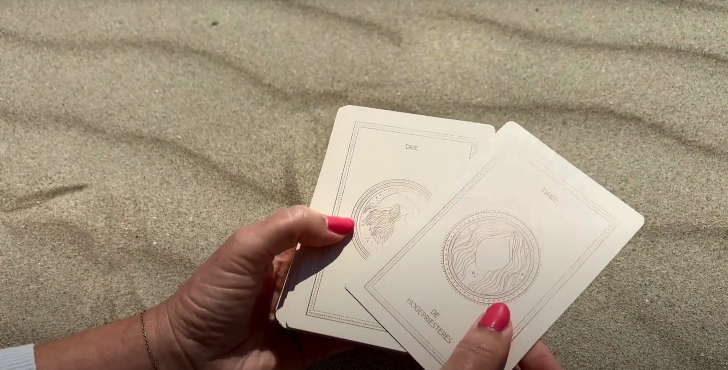 Vrouwenhand toont de tarotkaarten met boek van LE BOHO